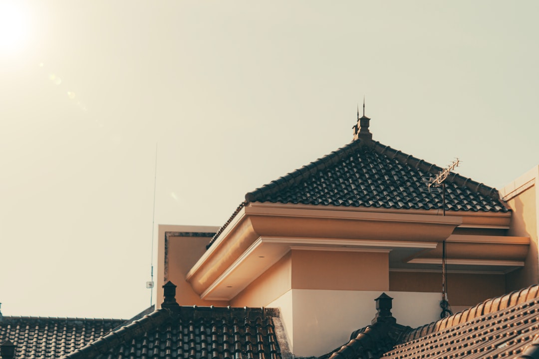 A classic suburban home, reminiscent of New England architecture, showcasing a perfectly installed new dark asphalt shingle roof on a bright, sunny day.