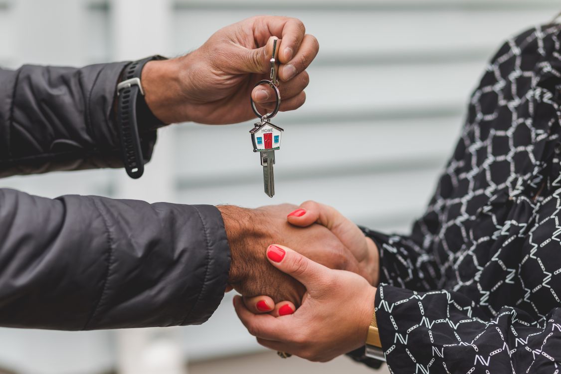 A professional roofer stands with a homeowner, pointing to an area of the roof and discussing the project, signifying trust and clear communication.